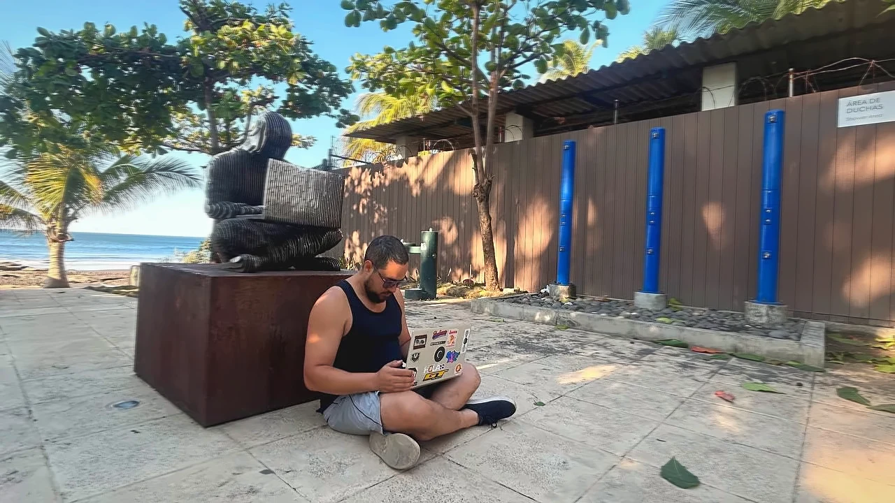 Pedro Vital trabajando con su computadora frente al mar.